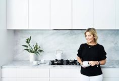 a woman standing in a kitchen holding a cup