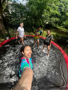 three young people are playing in the water on an above ground trampoline course