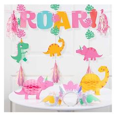 dinosaur party decorations on a table in front of a door with the word roar spelled out