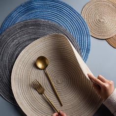 a person is holding a straw hat with gold spoons and fork on top of it