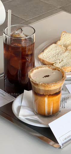 there is a tray with food and drinks on it that includes bread, ice tea and soda