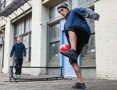 two men are playing frisbee in front of a building