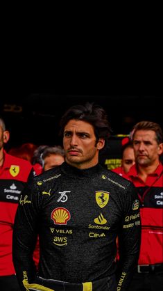 a man standing in front of a group of men wearing red and black uniforms with yellow trims