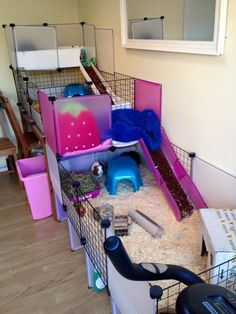 a cage filled with lots of toys and other items in a room next to a window