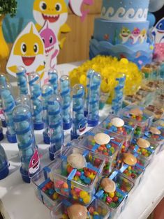 a table topped with lots of candy covered in blue and yellow candies next to cupcakes