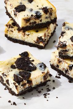 four pieces of cheesecake with oreo cookies and cream frosting on top, sitting next to each other