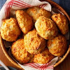 a basket filled with cheesy biscuits on top of a wooden table next to a fork