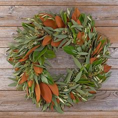 a wreath with orange and green leaves on a wooden background, hanging on a wall