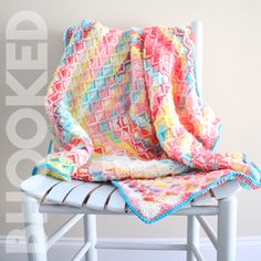 a crocheted blanket sitting on top of a white chair