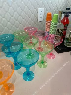 many different colored glasses are lined up on the counter