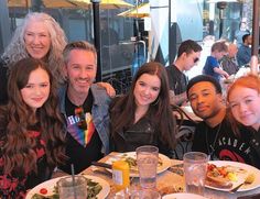 a group of people sitting at a table with plates of food