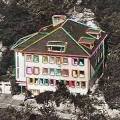 an aerial view of a multi - colored building with trees in the background