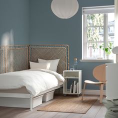 a bedroom with blue walls and white bedding in the corner, next to a window