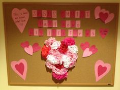 a bulletin board decorated with pink and red paper flowers, hearts and scrabbles