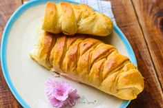 two croissants on a blue and white plate next to a pink flower