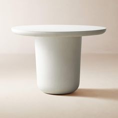 a white table with a round top on a beige background