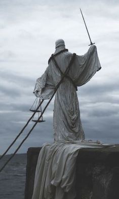 a statue that is sitting on the side of a wall with a pole in front of it