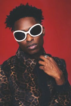 a woman in leopard print coat and sunglasses posing for a photo with her hand on her shoulder