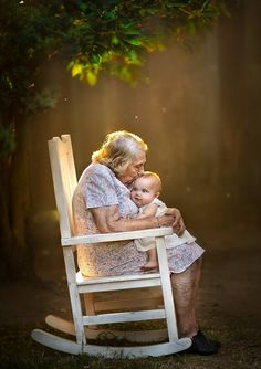 an older woman sitting in a rocking chair holding a baby