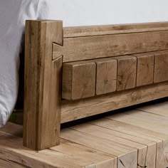 a wooden bed frame sitting on top of a wooden floor next to a white pillow