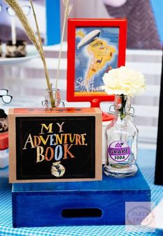 a table topped with vases filled with flowers and books on top of a blue box