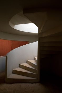 an open door leading to a spiral staircase in a building with orange curtains on the side