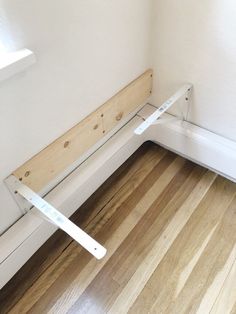 a wooden bench sitting on top of a hard wood floor next to a window sill