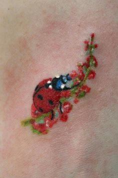 a ladybug tattoo on the back of a woman's neck with red flowers