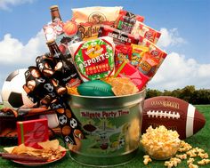 a football party gift basket with snacks, crackers, popcorn and sports balls on the grass