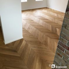 an empty room with wood flooring and brick wall