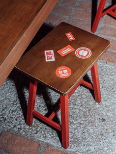 a small wooden table with stickers on it and some chairs in the back ground