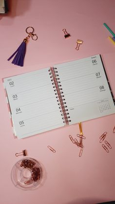 a pink desk with a calendar, ring binder and various office supplies on it