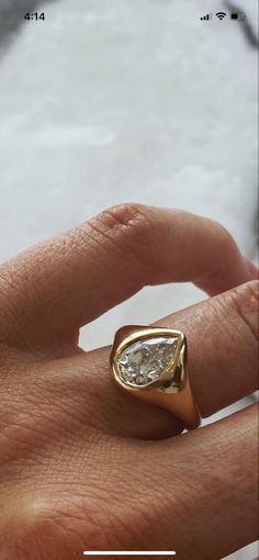 a person's hand with a gold ring on top of it and a diamond in the middle