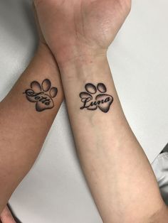 two people holding hands with tattoos on their arms and paw prints in the middle one has a dog's paw