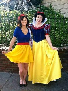 two women dressed as snow and snow white posing for a photo in front of a fence