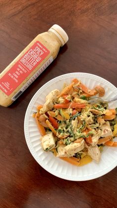 a white plate topped with chicken and veggies next to a bottle of mustard