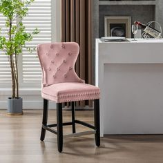 a pink chair sitting in front of a desk with a potted plant on it