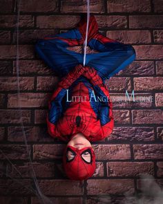 a spider man hanging upside down on a brick wall next to a person's face