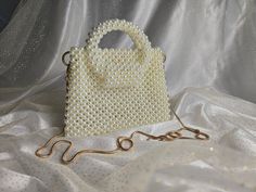 Handmade Pearl Beaded Bag with Round Handles and Golden-Toned Hardware This elegant handbag, crafted from pearl beads, features golden-toned hardware and a 47-inch removable chain. The magnetic closure adds convenience and ease of use. Our bags are 100% handmade. Each bag is unique and crafted with love for our customers. It takes 3-5 days to create one bag. A perfect gift for women, friend, family member or loved one. Ideal for any celebration, event, wedding or birthday party. This unique and Gold Rectangular Bag With Pearl Material, Rectangular Gold Bag With Pearl Material, Rectangular Gold Pearl Bag, Pearl Beaded Bag, Elegant Handbag, Round Handle, Beaded Bag, Beaded Bags, One Bag