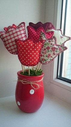 a red vase filled with lots of different types of cloths on top of a window sill