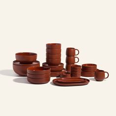 a stack of brown dishes and cups on a white background