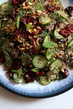 a blue and white plate topped with cucumbers, rice and nuts