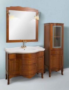 a bathroom vanity with a mirror above it and cabinet below the sink, in front of a blue wall