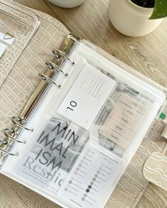 an open planner book sitting on top of a table next to a potted plant