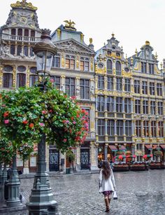 a woman is walking down the street in front of some buildings with flowers on them