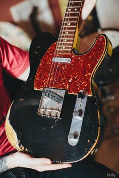 a person holding an electric guitar in their hand