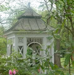 a white gazebo surrounded by trees and flowers