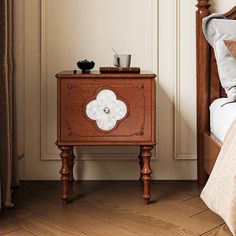 a small wooden cabinet sitting on top of a bed next to a night stand and nightstand