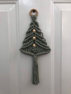 a christmas tree made out of yarn hangs on the front door with a wooden button