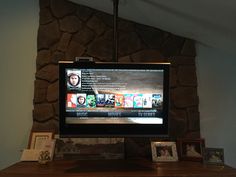 a flat screen tv sitting on top of a wooden dresser next to a stone wall